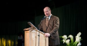 Physicist Dr. John Hagelin standing on stage at a podium