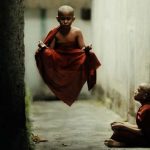 Young Buddhist monk levitation a few feet in the air with another young monk looking on