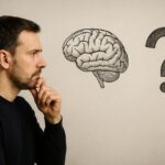 A thoughtful man contemplating a drawn human brain and question mark, representing consciousness as fundamental rather than produced by matter